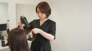 前ボケ越しにヘアブローする美容師