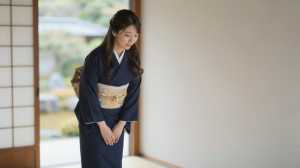 旅館で客を迎える着物姿の女性