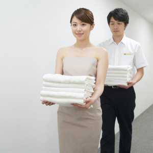 ホテル廊下でタオルを運ぶ男性スタッフ