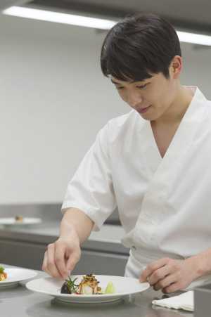 厨房で料理を盛り付けるシェフ