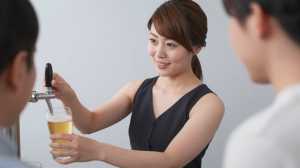 バーでビールを注ぎながら談笑する男性