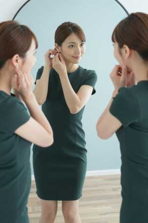 鏡でイヤリングを調整する女性