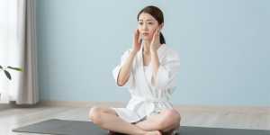 ヨガマットでフェイシャルマッサージをする女性