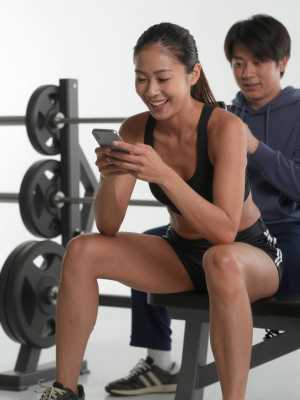 ジムのベンチでスマホを見る男性の顔