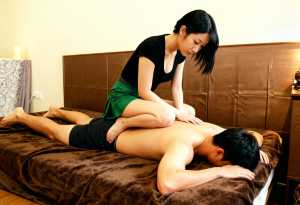 寝室のベッドに横たわっている男性に女性が親密なマッサージを施す様子を、トップダウンの...。