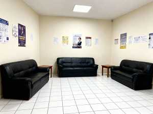 3 つの黒い革張りのソファと壁にポスターが置かれた待合室の写実的なレンダリング。