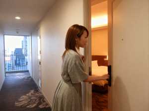 ライトグレーのドレスを着た長い茶色の髪の若い女性が、街のスカイラインを望むバルコニー...。