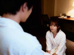 白いバスローブを着た若い女性がホテルの部屋の床に座り、目の前に注意深く座っている男性...。