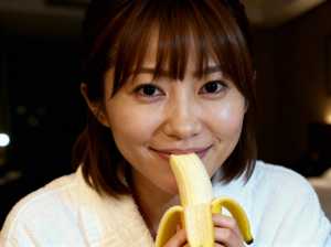 皮をむいたバナナを顔の前に持った、遊び心のある表情をしたアジア系の若い女性の接写写真。