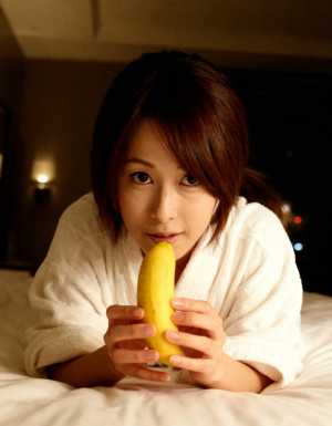 顔の前にバナナを持ってベッドに横たわる若い女性を、クローズアップ カメラ アングルか...。