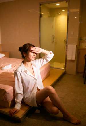 ホテルの部屋のベッドに座り、目を手で覆っている若い女性を横から撮影した写実的な写真。