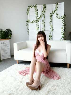 カジュアルなリビングルームのふわふわした白い敷物の上に座り、手で口を覆い、ピンクのレ...。