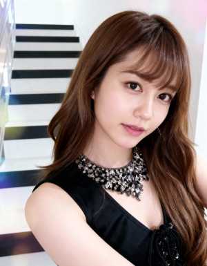 ウェーブのかかった茶色の長い髪を持ち、黒いノースリーブのドレスとステートメント ネッ...。