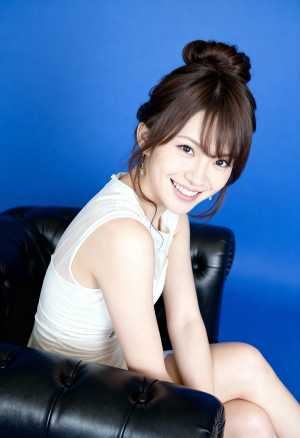 明るい青色の背景に黒い革張りのソファに座っている若い女性をポートレート角度から撮影し...。