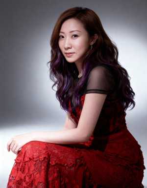 赤いレースのドレスを着て、グラデーションの背景に対して瞑想的なポーズで座っている、ウ...。