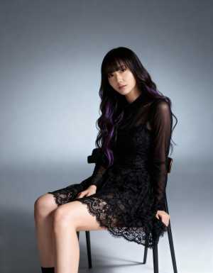 ミニマルな環境で黒いレースのドレスを着て椅子に座っている若い女性を正面カメラのアング...。