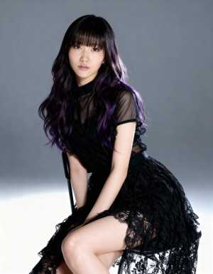 ウェーブのかかった長い黒髪と紫のハイライトを持つ若い女性が、黒いレースのドレスを着て...。