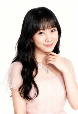 ウェーブのかかった長い黒髪と前髪を持ち、薄手の袖と繊細なネックレスが付いた淡いピンク...。