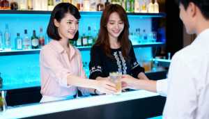 さまざまなアルコールのボトルを背景に、薄暗いバーのバーカウンターで握手する 2 人の...。