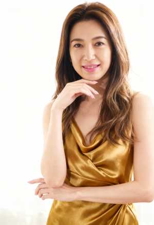 金色のシルクのドレスを着た、ウェーブのかかった茶色の長い髪を持つ若い女性のプロのポー...。