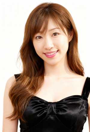 長くウェーブのかかった茶色の髪と白い肌を持ち、カメラに向かって微笑む若いアジア人女性...。