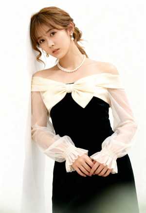 薄手の袖と大きなリボンが付いたフォーマルな衣装を着た若い女性が、無地の白い壁に向かっ...。