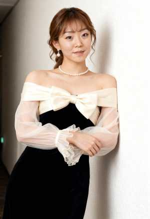 屋内の真っ白な壁に向かって立つ、正装をしたアジア系の若い女性のポートレート。