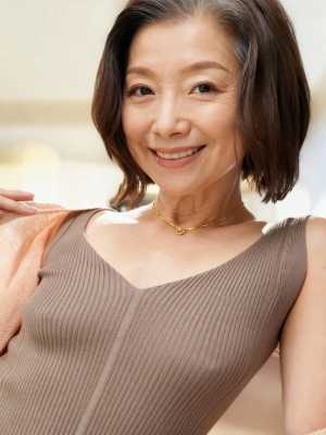 カメラに向かって微笑む、短く濃い茶色の髪を持つ中年のアジア人女性のポートレート。
