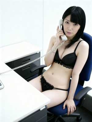 黒いレースのブラジャーとそれに合うパンティーを身に着け、机に座って電話で話している若...。