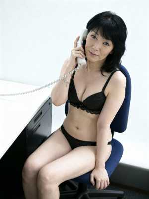 オフィス環境で青いオフィスチェアに座り、黒いレースのブラジャーとそれに合ったパンティ...。