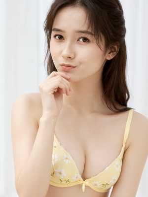 黄色の花柄のブラジャーを着て思慮深くポーズをとる若い女性をポートレートアングルから撮...。