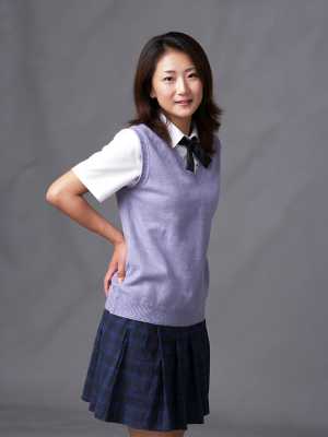 無地のグレーの背景に自信を持ってポーズをとる学生服を着た若い女性を、全身カメラ アン...。