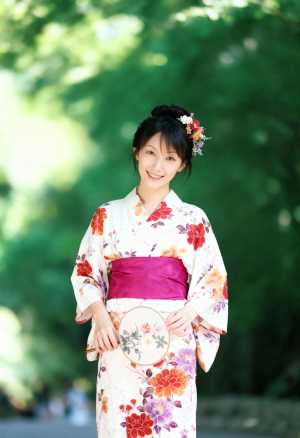 花柄の着物を着て公園に立つ、伝統的な和服を着た若い女性をポートレート カメラ アング...。