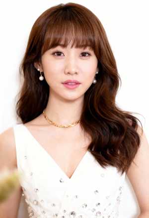 ウェーブのかかった茶色の長い髪と前髪を持ち、銀のスパンコールと真珠が付いた白いノース...。