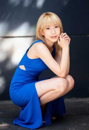 青いドレスを着た若い女性が瞑想的な表情でしゃがんでいる様子を、正面カメラのアングルか...。