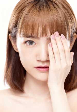 カメラを直接見つめながら片手で頭を抱え、思慮深い表情をしたアジア系の若い女性のクロー...。