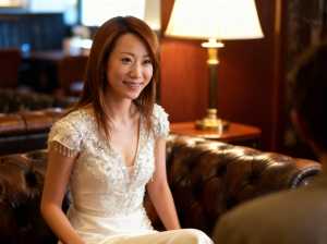 豪華なホテルのロビーで茶色の革張りのソファに座っている若いアジア人女性のポートレート。