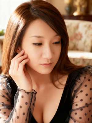 黒い水玉模様の薄手のトップスを着た、長くまっすぐな茶色の髪を持つ若いアジア人女性の写...。