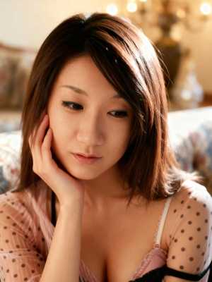 居心地の良いリビングルームのソファに座り、思慮深い表情を浮かべたアジアの若い女性の写...。