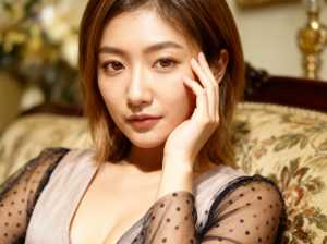 豪華なリビングルームのソファに座り、胸の谷間が見える大きく開いたネックラインの透けた...。