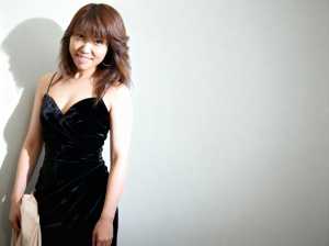 無地のライトグレーの壁に立っている黒いベルベットのドレスを着た若い女性を、ポートレー...。