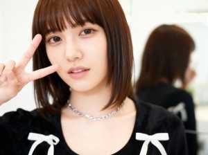 右手でピースサインをする若い女性をクローズアップカメラアングルから写実的に撮影したもの。