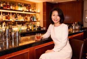 バーに座り、手にウィスキーのグラスを持った女性のポートレート。