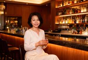 バーに座り、手にウィスキーのグラスを持った女性のポートレート。