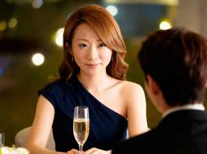 フォーマルな環境で男性の前でシャンパンを飲みながらテーブルに座る女性を、ポートレート...。