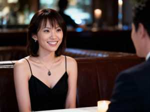 薄暗いレストランのテーブルに座り、フォーマルな雰囲気の中で男性に微笑みかけている女性...。