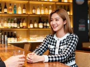 バーに座ってグラス一杯の水を前にカメラに向かって微笑む若い女性を、正面カメラのアング...。