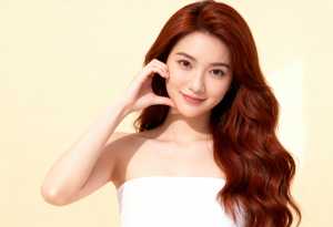 シンプルな明るい黄色の背景に対して、画像の中央に立つ、長くウェーブのかかった赤茶色の...。