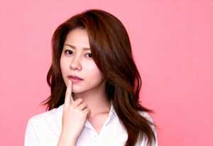 真っ白なピンク色の背景に、白い襟付きのシャツを着た、長くまっすぐなダークブラウンの髪...。