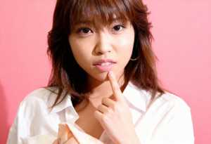 白い襟付きのシャツを着た、長く真っ直ぐな濃い茶色の髪と前髪を持つ若いアジア人女性の接写。